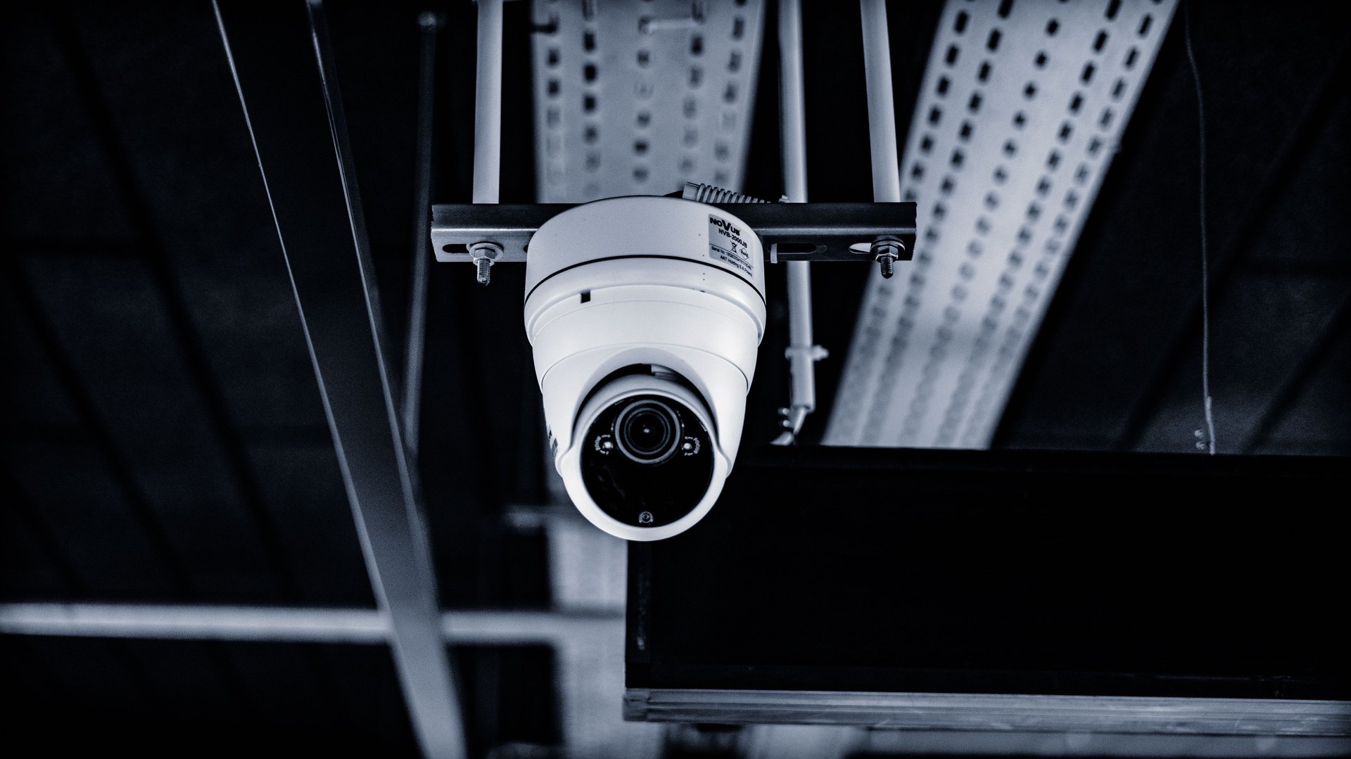 Cámara dome de seguridad CCTV montada en techo industrial con conduit metálico de fondo