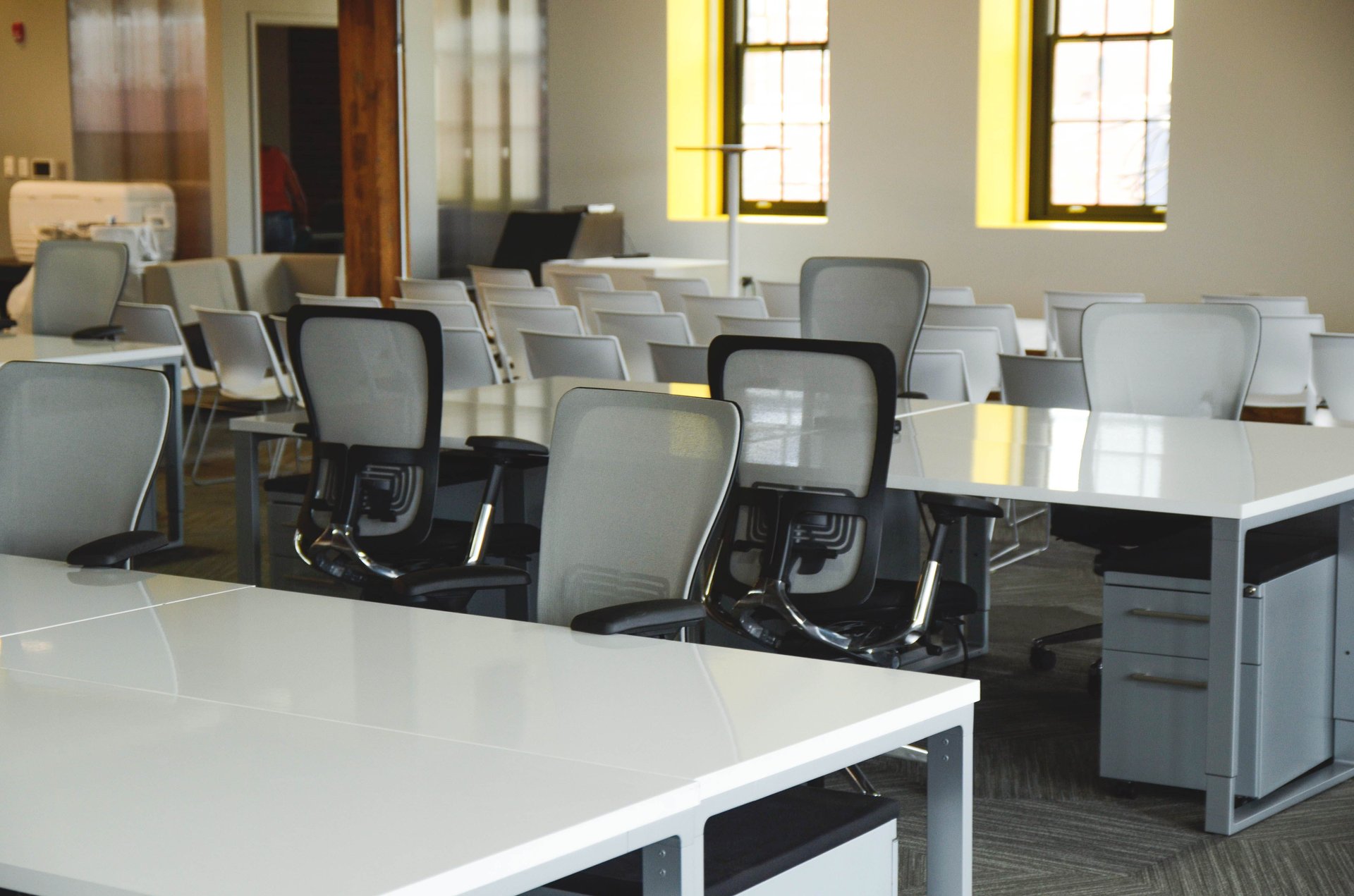 Sala de oficina corporativa con escritorios parcialmente vacíos bajo luz natural tenue — atmósfera de reestructuración organizacional