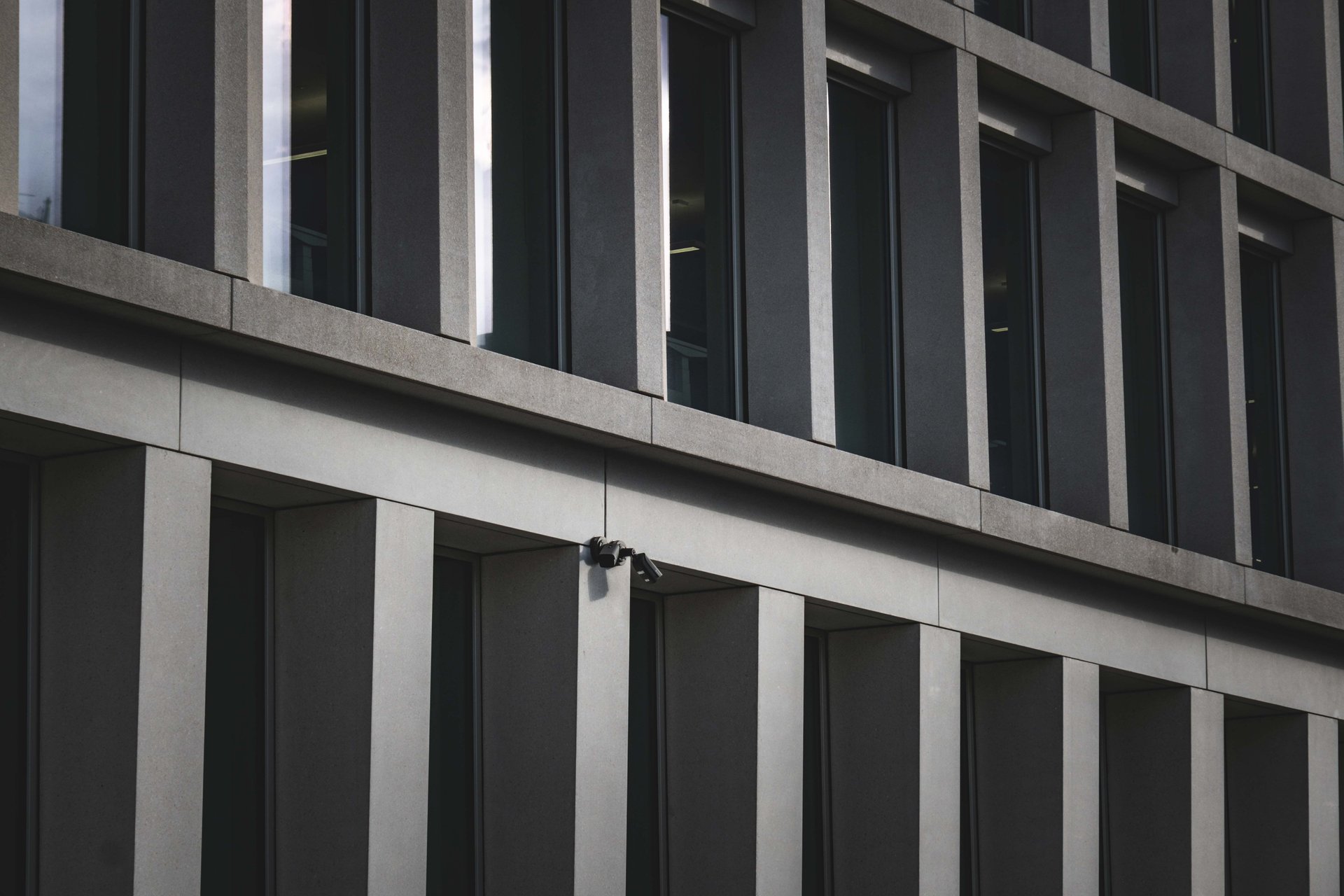 Edificio legislativo en una capital latinoamericana con una cámara de seguridad montada en la fachada — la frontera entre el marco regulatorio que un RFP debe citar y el footage que el vendor captura