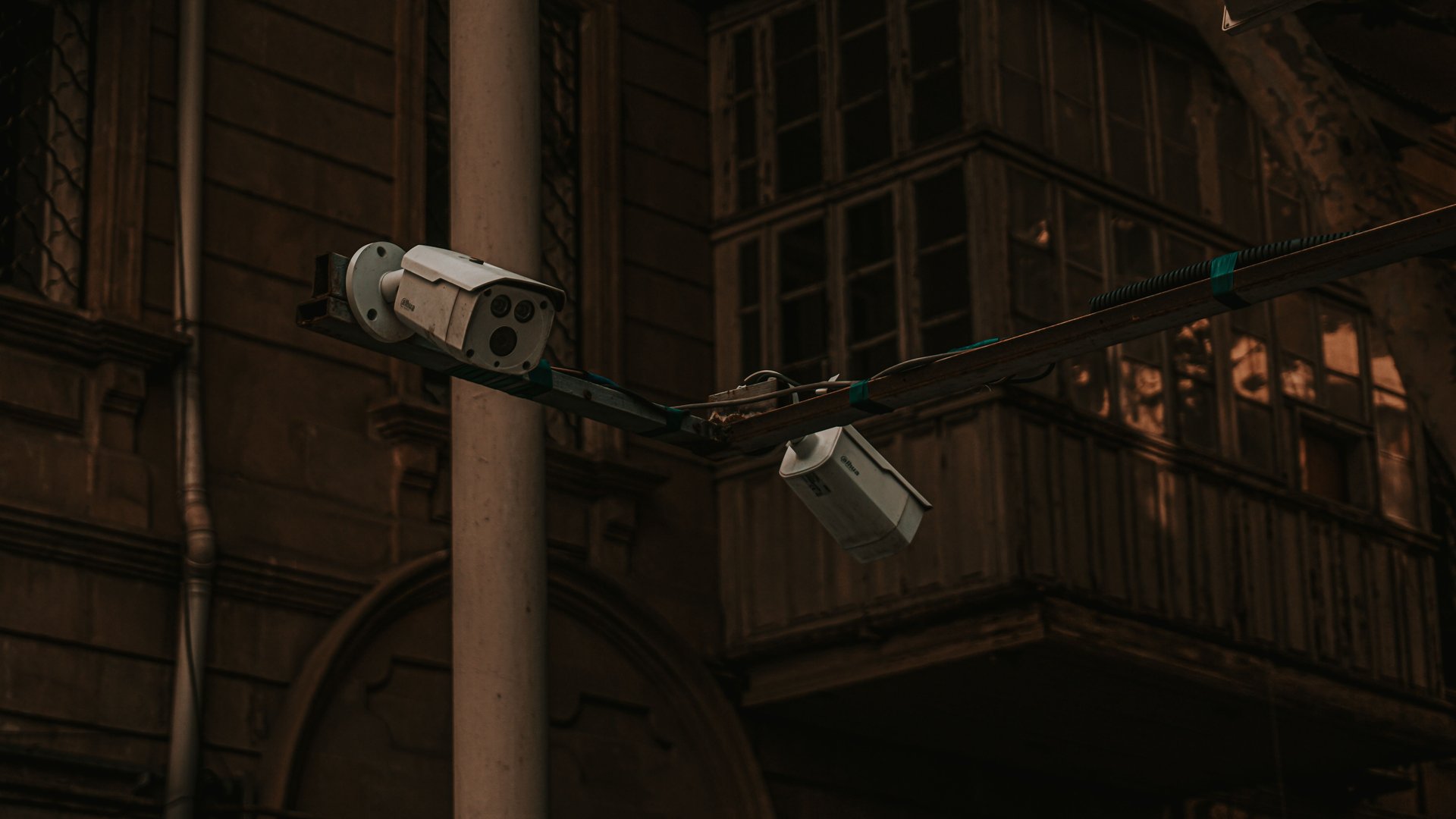 Cámaras CCTV montadas en poste frente a edificio institucional — vigilancia urbana sobre arquitectura pública