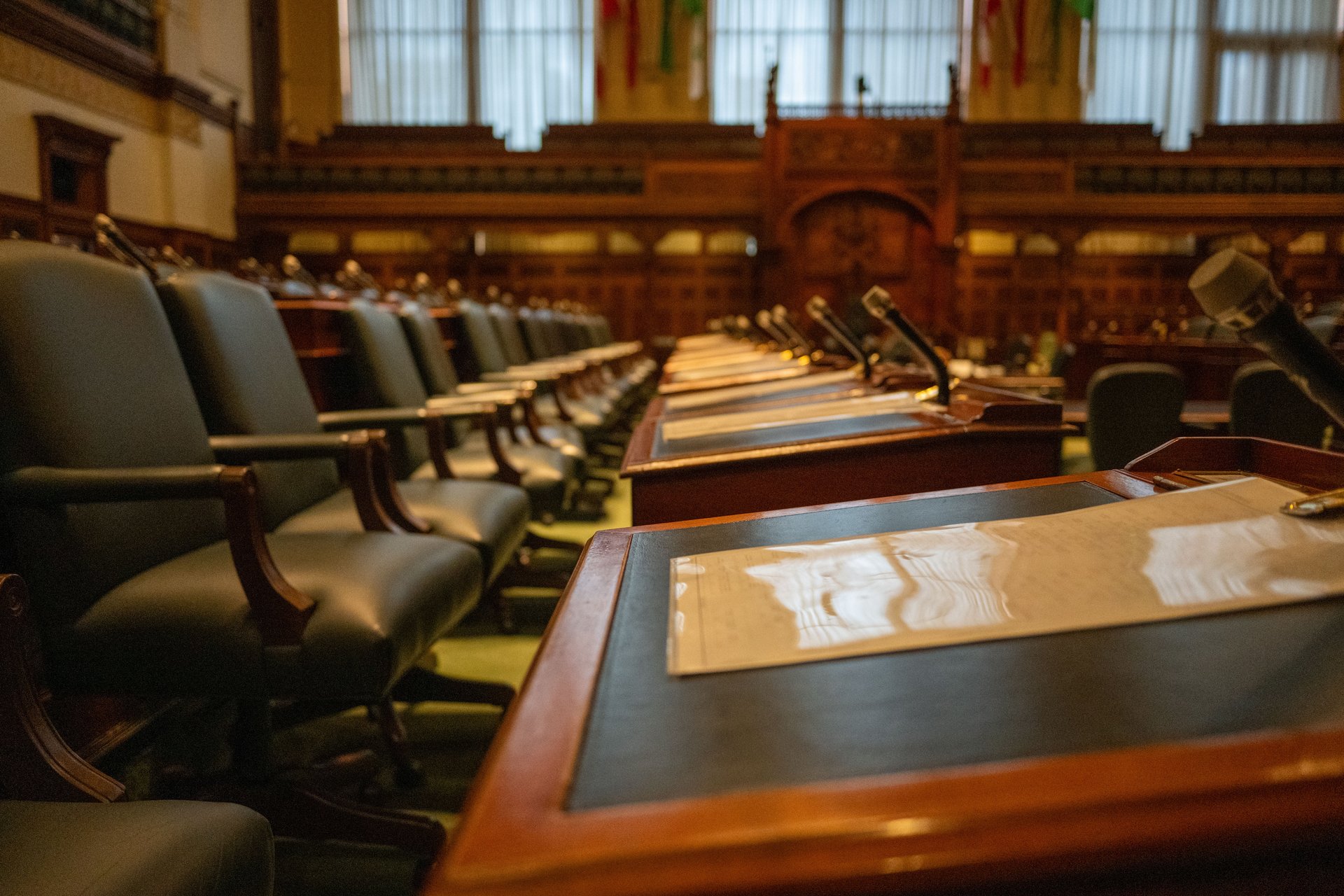 Asientos vacíos de un comité del Senado de EE.UU. — fila de sillas de cuero frente a escritorio de testigos con micrófonos preparados para los CEOs de Flock, Axon, Motorola y Verkada que testificarían el 23 de septiembre